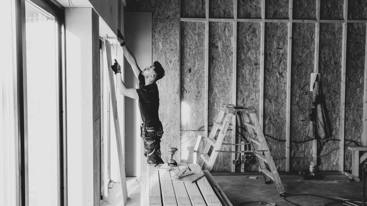 Artisan travaillant sur une ossature interieure en cours d'isolation