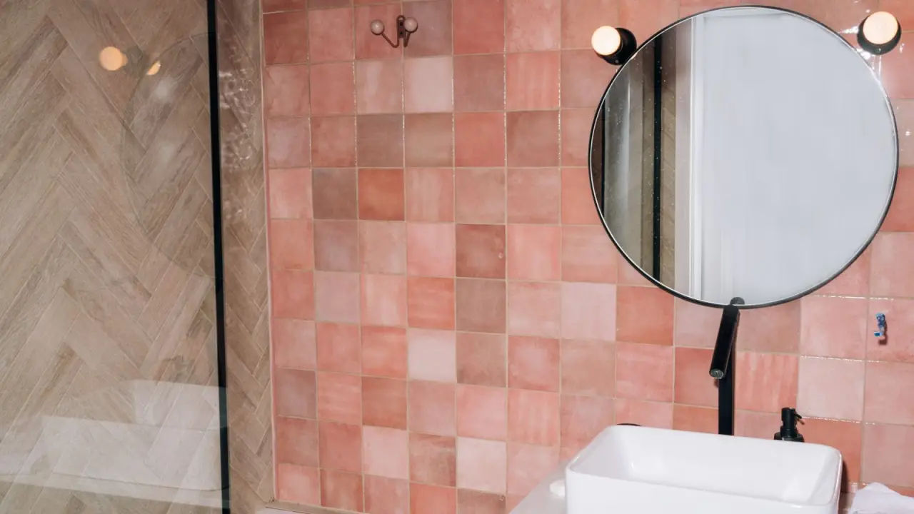 Salle de bain avec mur en carreaux terracotta, vasque et miroir rond